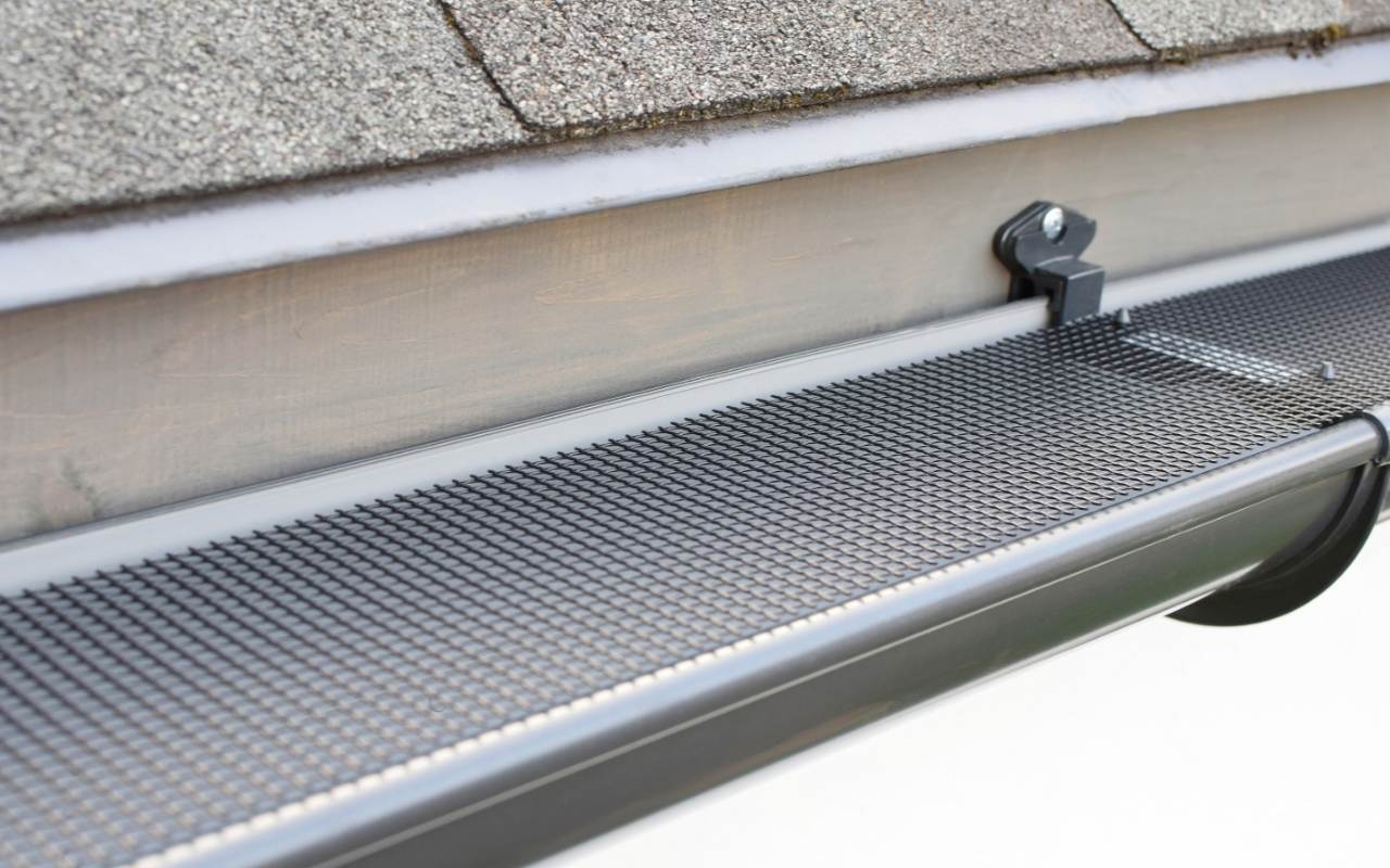 Technician clearing roof gutters to prevent rainwater backup