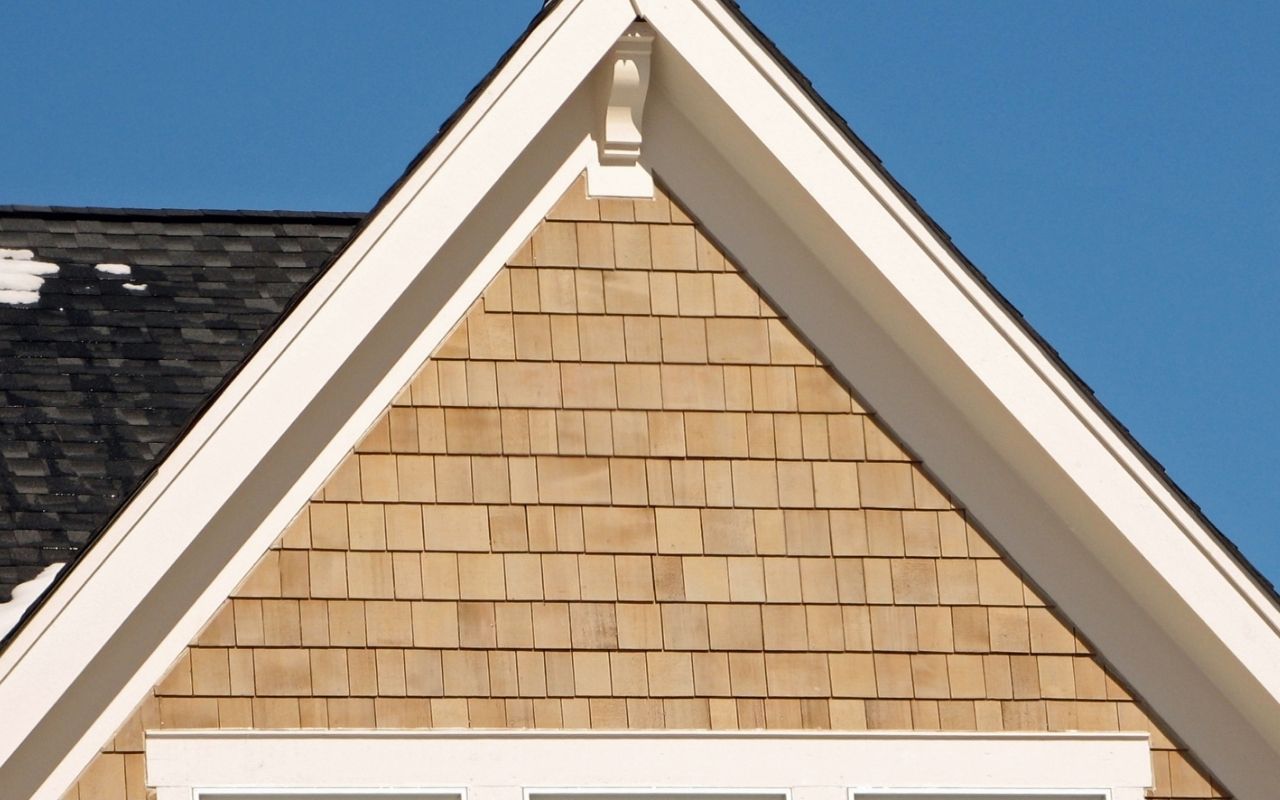 Home exterior with taupe vinyl siding shingles and white trim on gable roof